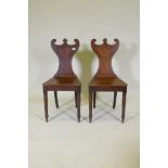 A pair of Regency oak hall chairs with shaped backs, raised on turned tapering supports, 88cm high