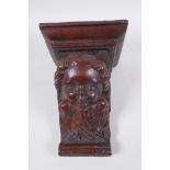 A C17th adapted carved oak bracket/term, with cherub mask decoration, 23cm
