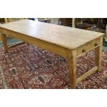 A large Victorian pine scullery table with plank top and end drawers, raised on square tapering