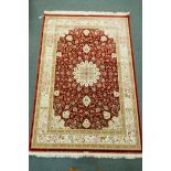 A Persian red ground full pile bamboo silk carpet with central floral medallion design and cream