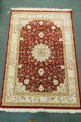 A Persian red ground full pile bamboo silk carpet with central floral medallion design and cream