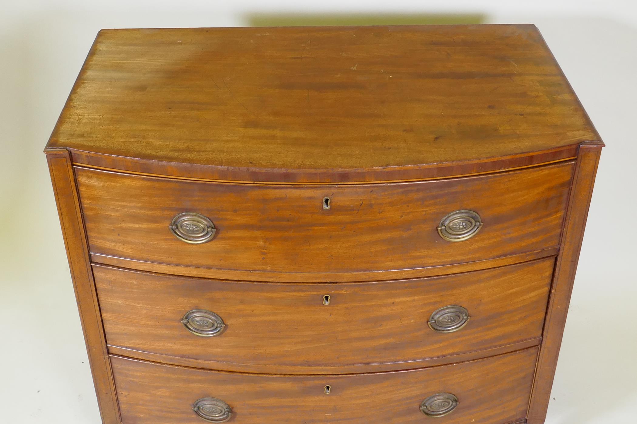 A C19th mahogany Sheraton style bow front chest of three long drawers with brass plate handles, - Image 3 of 9