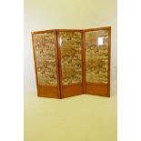A C19th satinwood triple fold screen with glazed panels inset with a vintage printed textile