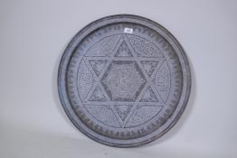A Middle Eastern brass tray, engraved with Islamic calligraphy and geometric designs, 63cm diameter