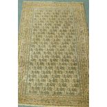 A Middle Eastern hand woven wool carpet with all over geometric designs on a faded terracotta field,