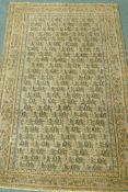 A Middle Eastern hand woven wool carpet with all over geometric designs on a faded terracotta field,