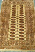 A Bokhara wool rug with geometric designs on a gold field, 180 x 120cm