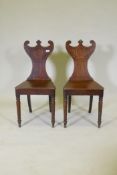 A pair of Regency oak hall chairs with shaped backs, raised on turned tapering supports, 88cm high