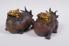 A pair of Chinese filled bronze temple lions with gilt details, 12cm long
