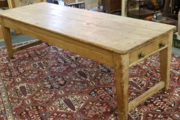 A large Victorian pine scullery table with plank top and end drawers, raised on square tapering
