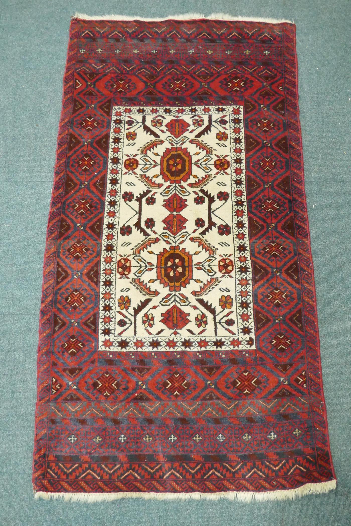 A Middle Eastern hand woven rug with red borders and central panel, with geometric floral designs