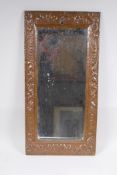 An antique beaten copper wall mirror with repousse swag decoration, 56 x 28cm