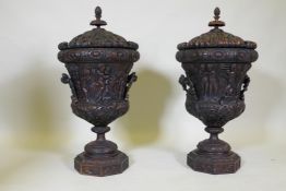 A pair of carved wood urns with covers, the bodies decorated with a Bacchanalian procession of
