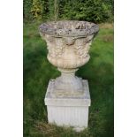 A pair of composite stone urns on plinths