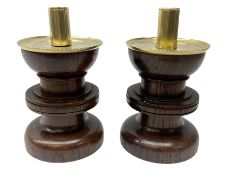 Pair of Arts and Crafts turned oak candlesticks with brass mounted sockets and drip pans