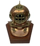 Copper and brass miniature diving helmet upon a wooden plinth