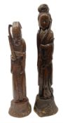 Two large hardwood Oriental figures carved as a man and woman donning robes upon naturalistic plinth