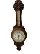 An English 1930�s solid oak carved hall barometer in a scroll shaped carved case with relief carving