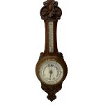 An English 1930�s solid oak carved hall barometer in a scroll shaped carved case with relief carving