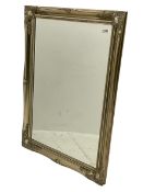 Bevelled mirror in swept silvered frame decorated with foliate cartouches