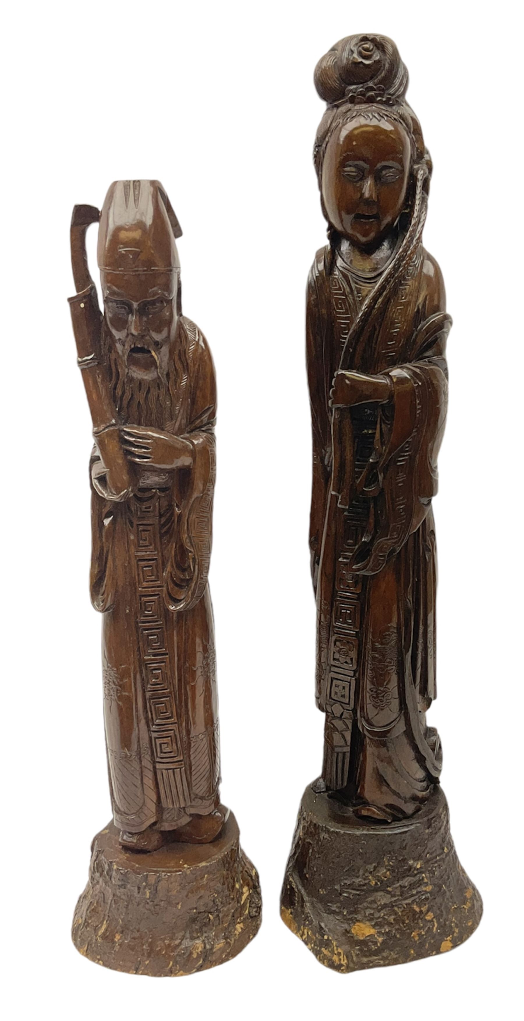 Two large hardwood Oriental figures carved as a man and woman donning robes upon naturalistic plinth