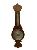 An early 20th century oak cased aneroid barometer in a decorative form with inlay in the arts and cr