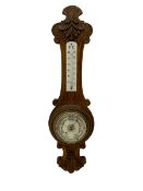 A carved oak cased aneroid barometer with a 5” register