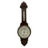 An English carved oak cased aneroid barometer with an 8'' porcelain dial