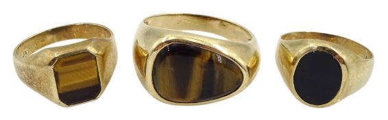 Two gold tigers eye rings and a black onyx signet ring