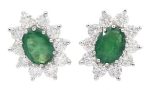 Pair of yellow and white gold oval emerald and round brilliant cut diamond cluster stud earrings