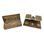 19th century cased set of Chemists' weights and tweezers and a set of brass postal scales on a foote