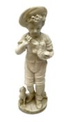 Marble figure of a boy donning a hat stood feeding a pigeon in his left arm with a hound seated by h