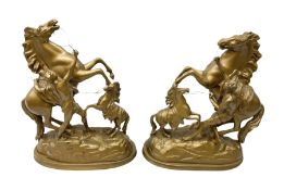 Pair of spelter mantel figural group sculptures of rearing horses and handlers on oval bases