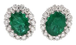 Pair of white gold oval emerald and round brilliant cut diamond stud earrings