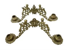 Two ornate brass wall sconces with twin branches modelled with cherubs playing trumpets