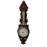 A 1920s oak cased patented aneroid barometer with openwork decorative carving