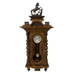 A late 19th century German wall clock in a mahogany case with a decorative carved pediment
