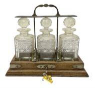 Edwardian oak tantalus with silver plated locking mechanism and three square sided glass decanters