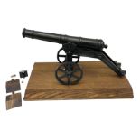 Black painted heavy cast metal model of a cannon on field carriage L41.5cm; loose mounted on oak bas
