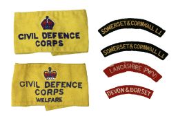 Pair of Civil Defence Corps armbands; and three cloth shoulder titles for Somerset & Cornwall L.I (2