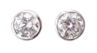 Pair of platinum bezel set round brilliant cut diamond stud earrings