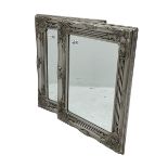 Pair bevelled edge wall mirrors in swept silvered frames decorated with ornate cartouches