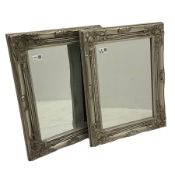 Pair bevelled edge wall mirrors in swept silvered frames decorated with ornate cartouches