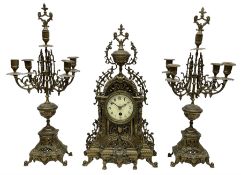 A late 19th century profusely decorated brass cased timepiece mantle clock with two matching five li