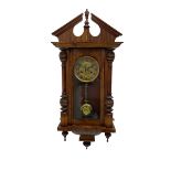 German early 20th century wall clock in a mahogany case with an architectural pediment and turned fi