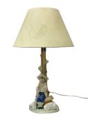 Nao table lamp modelled as a boy playing the flute upon logs with two recumbent sheep at his feet