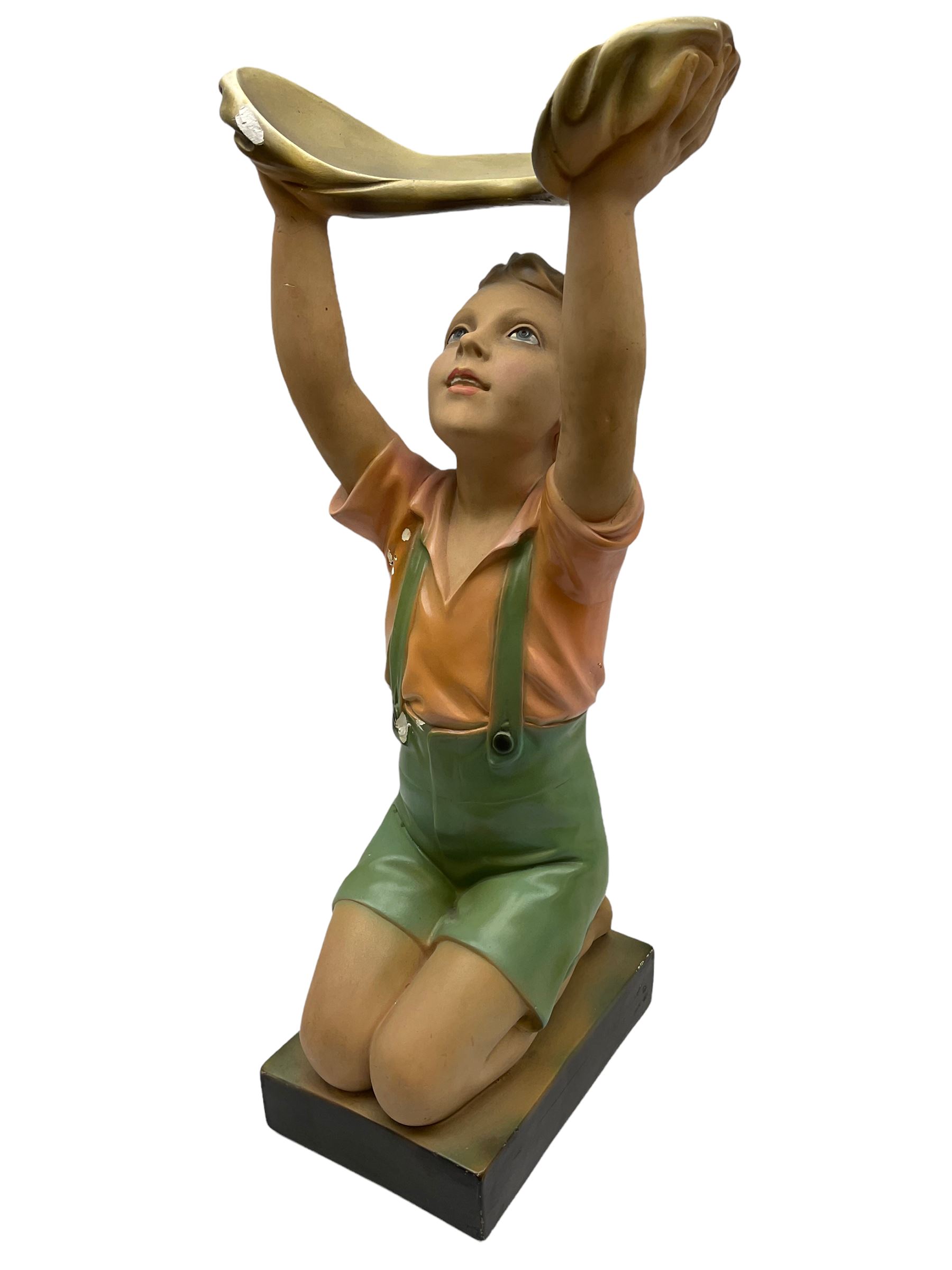 Art Deco plaster figure modelled as a young boy kneeling with his arms above his head holding a dish