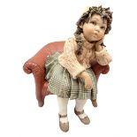 Italian Sibania Capodimonte figure of a young girl seated upon red chair with one hand supporting he