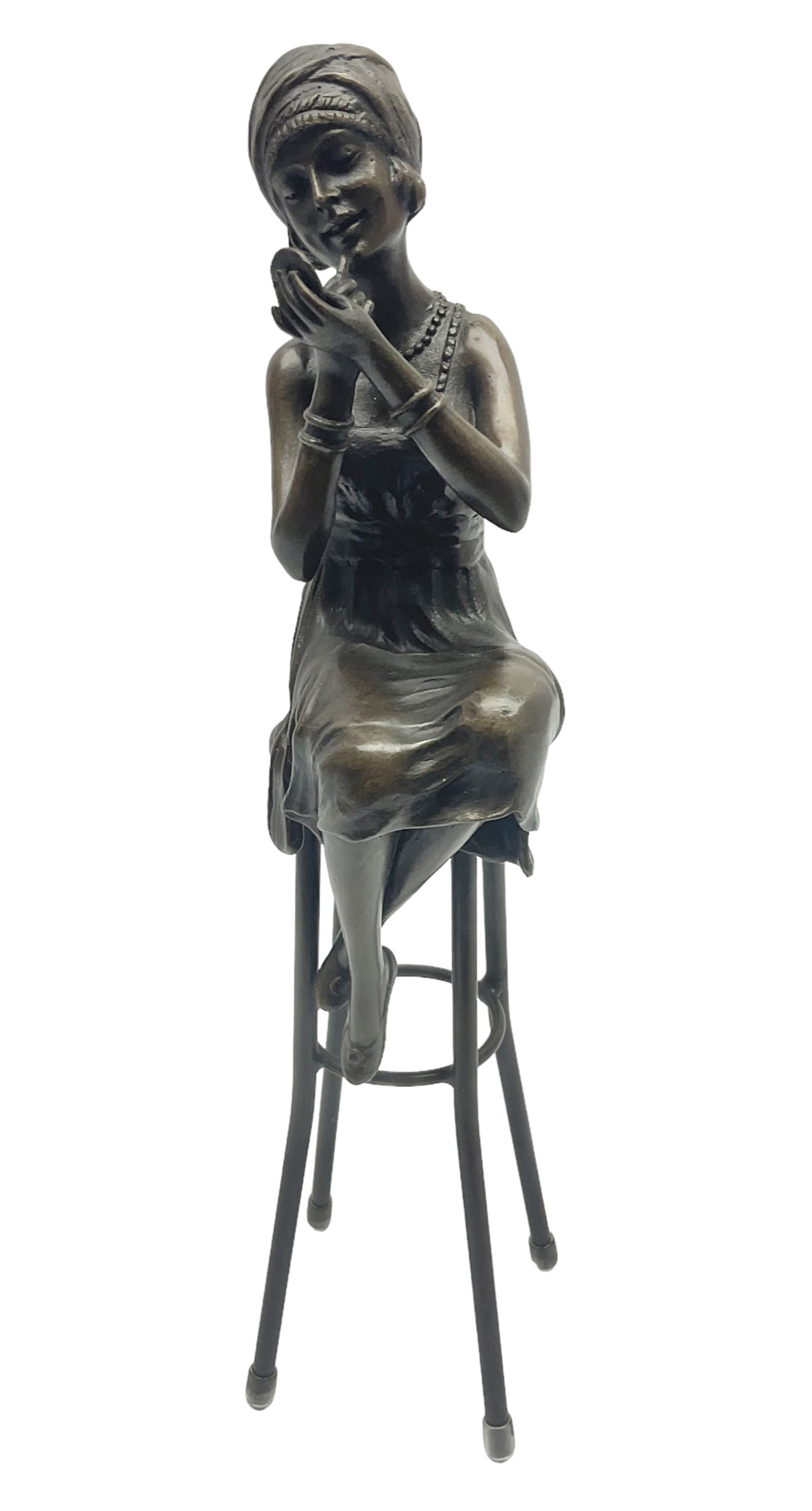 Art Deco style bronze figure of a lady seated on a stool applying lipstick