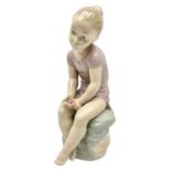Large Nao figure modelled as a young girl seated upon a rock holding a rose